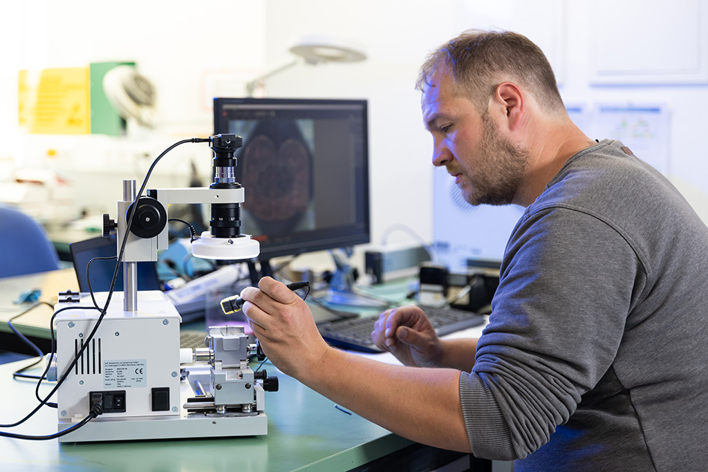 Student bei rmw prüft Bauteil per Mikroskop